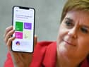 First Minister Nicola Sturgeon views the new Covid-19 track and trace app on a phone at the Scottish Parliament.