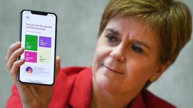 First Minister Nicola Sturgeon views the new Covid-19 track and trace app on a phone at the Scottish Parliament.