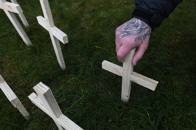 A man leaves a cross in memory of his brother at a memorial event for victims of drugs (Picture: John Devlin)