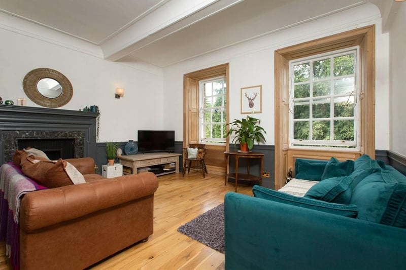 The spacious living area, which is flooded in natural light through the large timber framed windows. The room offers excellent options for various furniture arrangements and the grand open fireplace provides a tasteful focal point.
