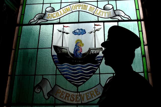 A police constable silhouetted against the crest of Leith stained glass window, at Leith Police Station