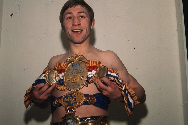Ken holding a collection of boxing belts including the Lonsdale Belt and World Title belt in 1974.