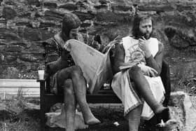 A chainmail-clad John Cleese reads a newspaper while Graham Chapman smokes a quiet pipe on the set of Monty Python and the Holy Grail (Picture: John Downing/Express/Getty Images)