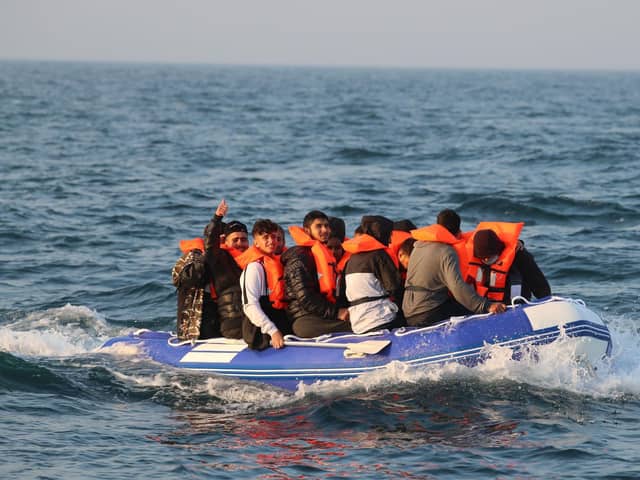 A man gives a thumbs up as he sits with a group of people, thought to be migrants, crossing The Channel in a small boat headed in the direction of Dover