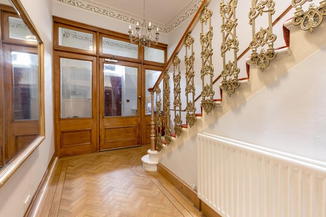 The entrance vestibule and hallway with a stunning staircase with cast iron balusters and curving wooden handrail.