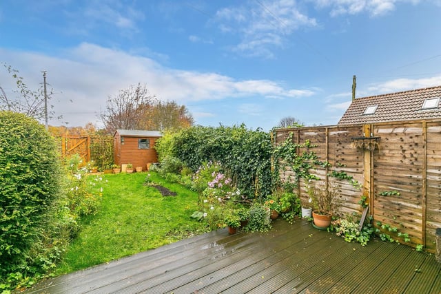 To the rear is a secluded and enclosed garden with wooden decking, lawn and a store shed.