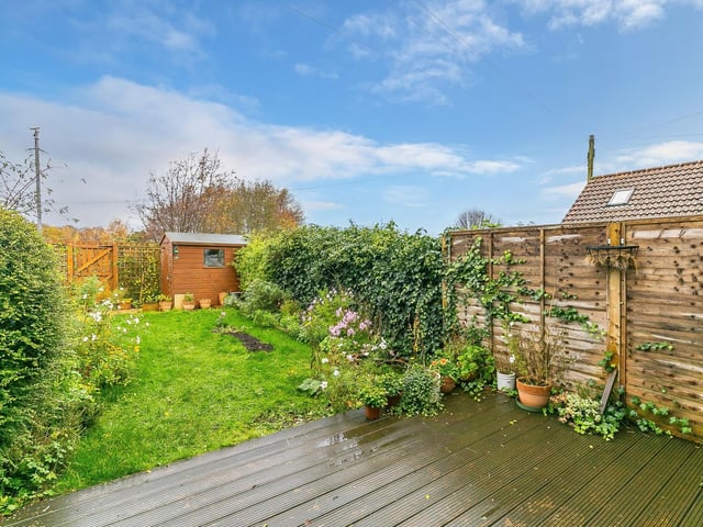 To the rear is a secluded and enclosed garden with wooden decking, lawn and a store shed.