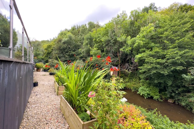 The property also has a sizeable, private decked patio with glass balustrade, pergola and space to entertain, together with access down to the riverside garden with its beautiful array of flowers & steps to the water's edge.