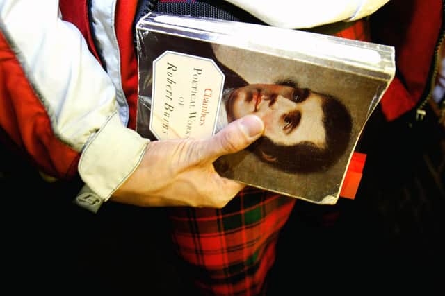 Man with traditional Scottish tartan holds a book with Robert Burns face on it at Burns Night January 24, 2004 (Picture: Graeme Robertson/Getty Images)