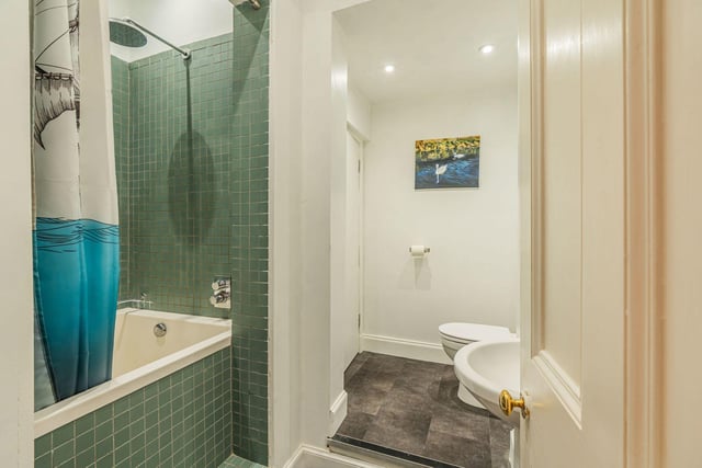 The partially-tiled bathroom suite with an over-bath rainfall shower and heated towel rail.