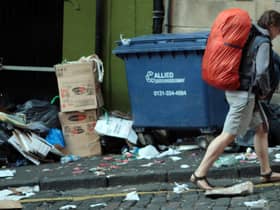 A backpacker walks through a rubbish-strewn Edinburgh street (Picture: David Cheskin/PA)