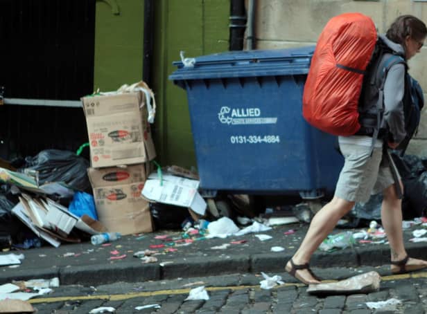 A backpacker walks through a rubbish-strewn Edinburgh street (Picture: David Cheskin/PA)
