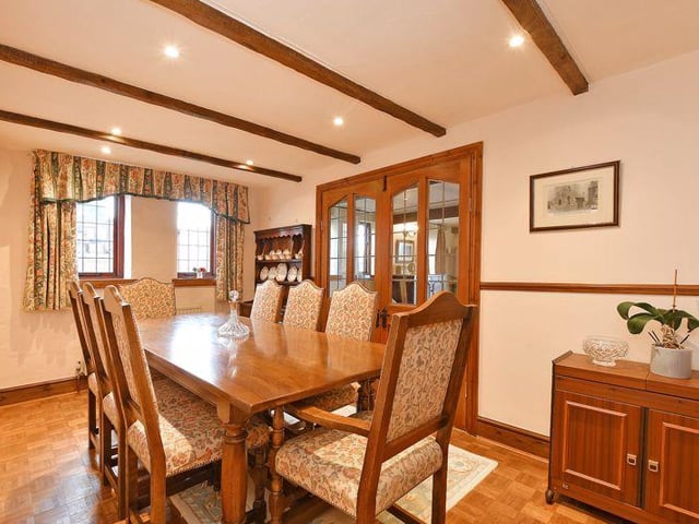 From the lounge, glazed panel French doors open into a dining room with a polished parquet wood floor and two side windows.