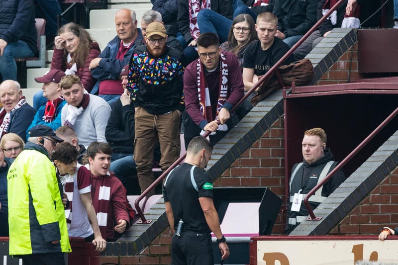 Walsh consults the VAR monitor, with Hearts fans trying to get a look too