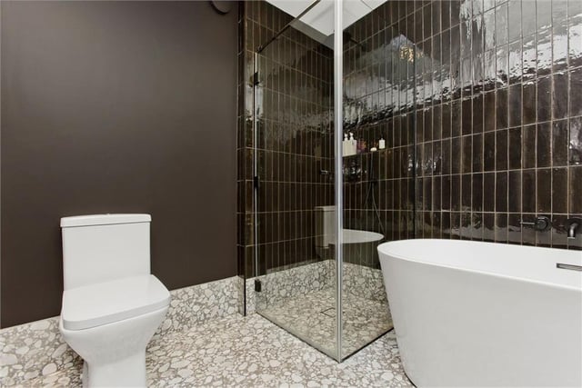 The striking bathroom has a double-ended freestanding bathtub, separate walk-in shower enclosure, twin floating washbasins, and a toilet.