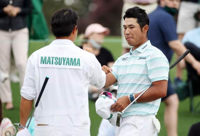 Hideki Matsuyama with his caddie after finishing on the 18th green in the third round of the Masters at Augusta National Golf Club. Picture: Kevin C. Cox/Getty Images.