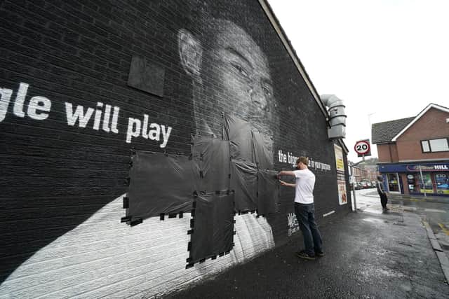 Ed Wellard, from Withington, tapes bin liners across offensive wording on the mural of Manchester United striker and England player Marcus Rashford on the wall of the Coffee House Cafe on Copson Street, Withington, which appeared vandalised the morning after the England football team lost the UEFA Euro 2021 final.