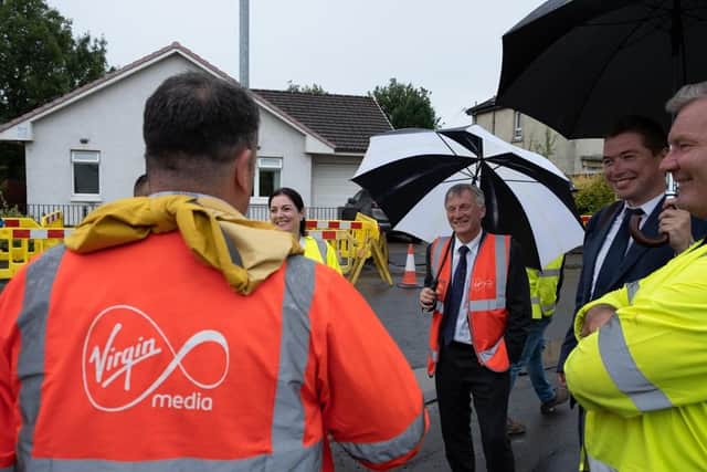 Scottish business minister Ivan McKee, pictured with black and white brolly, visited a dig site in Glasgow to follow the process of laying fibre cables to reach new homes in the area.