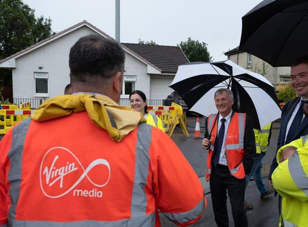 Scottish business minister Ivan McKee, pictured with black and white brolly, visited a dig site in Glasgow to follow the process of laying fibre cables to reach new homes in the area.