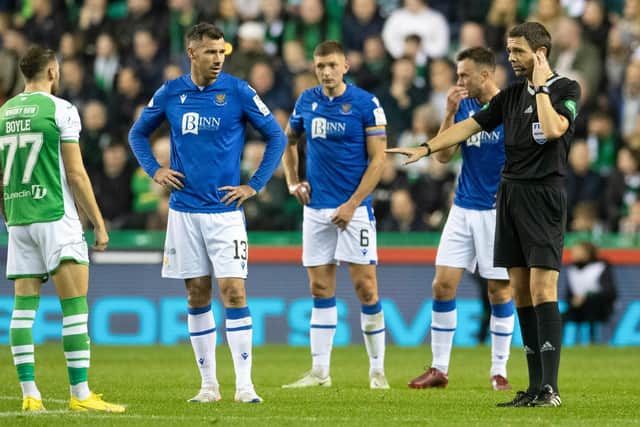 Referee Kevin Clancy receives instructions from the VAR officials after Martin Boyle is booked for diving.