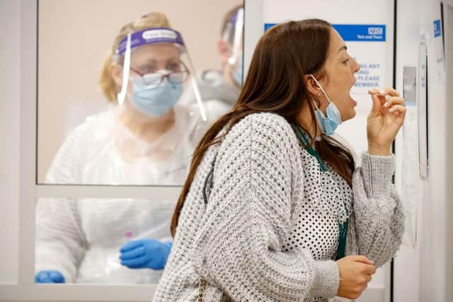 A woman uses a swab to take a sample from her mouth at a NHS Test and Trace Covid-19 testing unit at the Civic Centre in Uxbridge, Hillingdon, west London on May 25, 2021. Photo by ADRIAN DENNIS/AFP via Getty Images