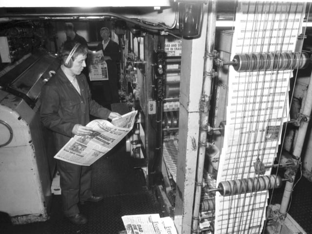 A Scotsman Publications employee wearing ear protectors checks a copy of the Evening News as it comes off the presses in the basement of the newspaper's headquarters at North Bridge Edinburgh, January 1990.