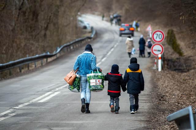 A woman with two children and carrying bags walk on a street to leave Ukraine after crossing the Slovak-Ukrainian border. The UK has imposed further sanctions on prominent Russians, including media figures and military leaders.