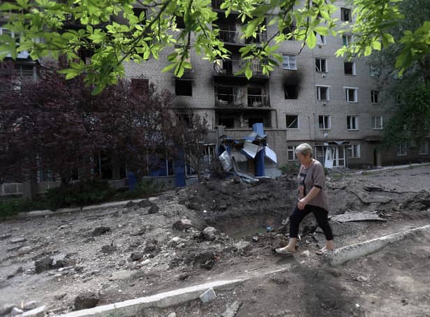 A woman walks past a shell crater in front of a damaged residential building in the town of Siversk, Donetsk region, on June 23, 2022, amid Russia's military invasion launched on Ukraine. -  via Getty Images