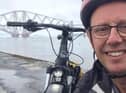 Bruce Whitehead poses for a selfie with his electric bike and the Forth Bridge in the background