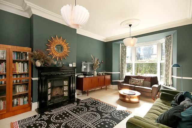 The fireplace, ceiling detail, dark green-painted walls and bay window all catch the eye in the lounge.