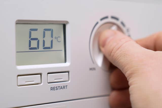 A homeowner turning down the temperature of a gas boiler.