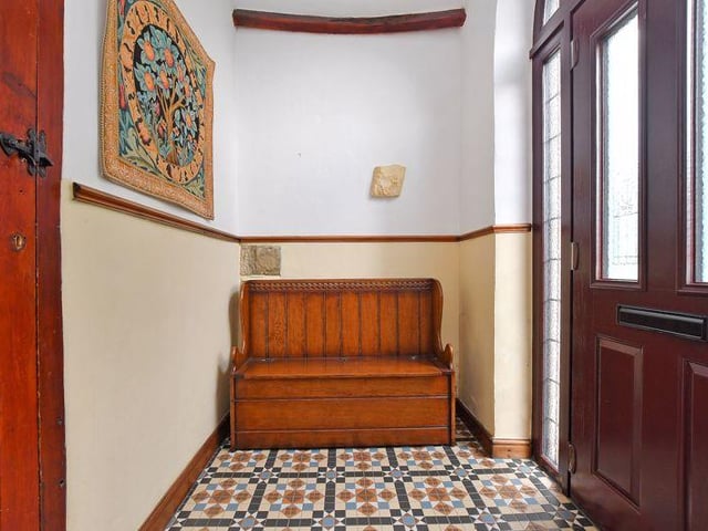 A traditional monks bench has been positioned in the entrance lobby, which also contains a tiled floor and exposed roof timbers.