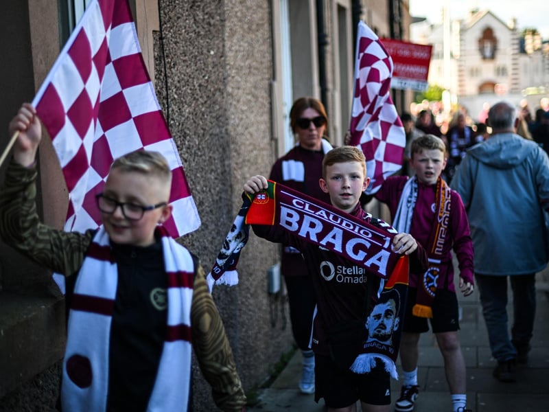 Young Hearts fans hold flags and banners as they arrive before the start (Photo by ANDY BUCHANAN / AFP via Getty Images)