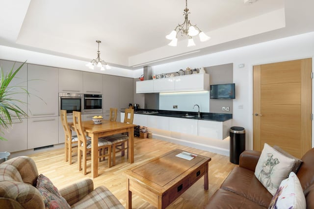 Spacious dining/kitchen/family room with wide range of designer taupe and white high gloss units & integrated appliances with black granite worktops and doors leading to the balcony.