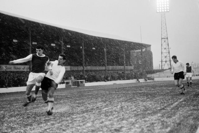 Players brave a snow-covered pitch during a Hibs v Clyde match at Easter Road in December 1964.