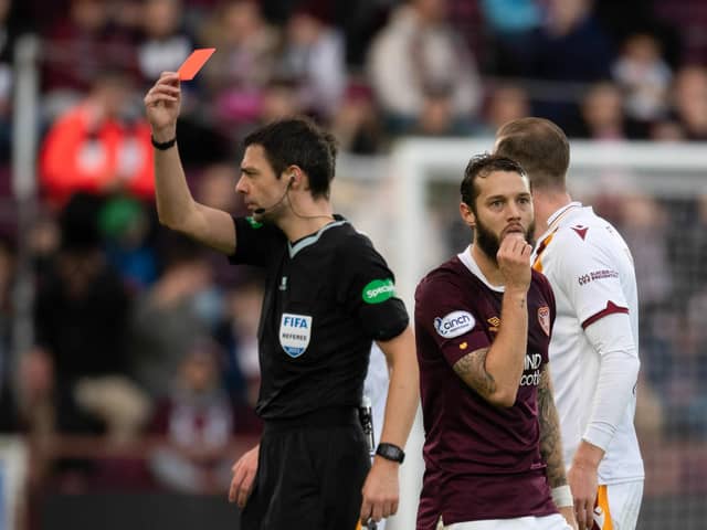 Referee Kevin Clancy shows Hearts midfielder Jorge Grant a red card.