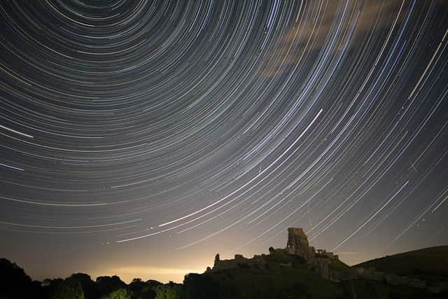 Satellites, planes and comets transit across the night sky under stars that appear to rotate above Corfe Castle (Photo: Dan Kitwood/Getty Images)