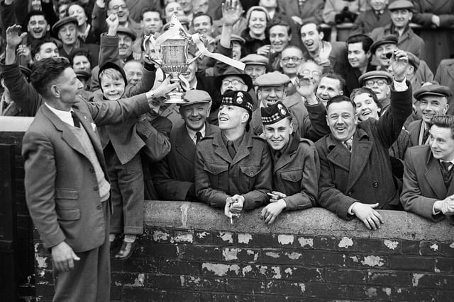 Hearts groundsman Mathie Chalmers shows the Scottish Cup to a section of the crowd at Tynecastle in 1956. Hearts had just beaten Celtic at Hampden Park in the Scottish Cup final.