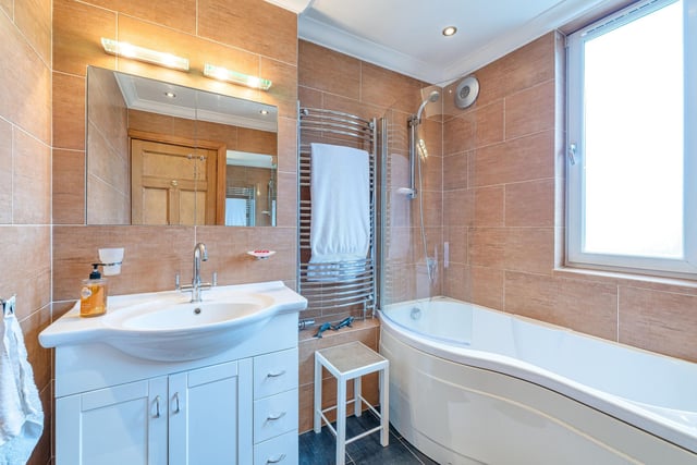 The family bathroom with white curved bath featuring a wall-mounted shower.