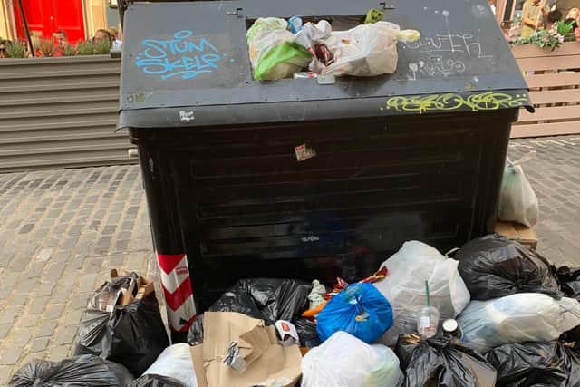 Rubbish heaped up on the pavement alongside bins on Cockburn Street.