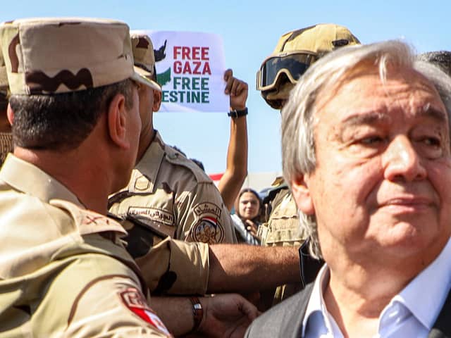 Protesters raise signs in solidarity with Palestinians in the Gaza Strip as Egyptian army officers and bodyguards escort United Nations Secretary-General Antonio Guterres to his vehicle (Image: KEROLOS SALAH/AFP via Getty Images)