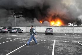 A Ukrainian serviceman walks past as fire and smoke rises over a damaged logistic center after shelling in Kyiv, Ukraine, March 3, 2022.  (AP Photo/Efrem Lukatsky, File)