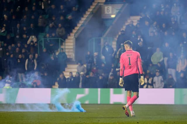 Matt Macey looks on as a smoke bomb smoulders on the Easter Road turf