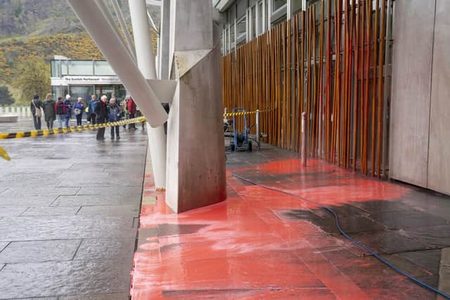 Workmen clean up red paint that was thrown by climate activists outside the Scottish Parliament, Edinburgh. (Photo credit: Jane Barlow/PA Wire)