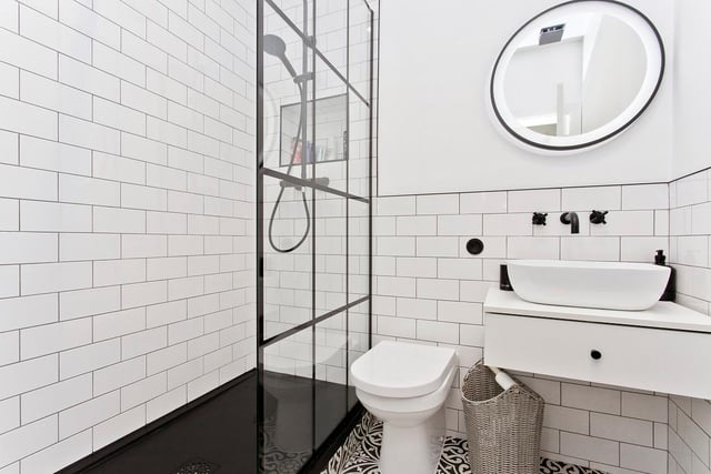 The shower room boasts stylish tiling and contemporary fixtures and fittings, including a walk-in double shower enclosure and modern vanity storage.