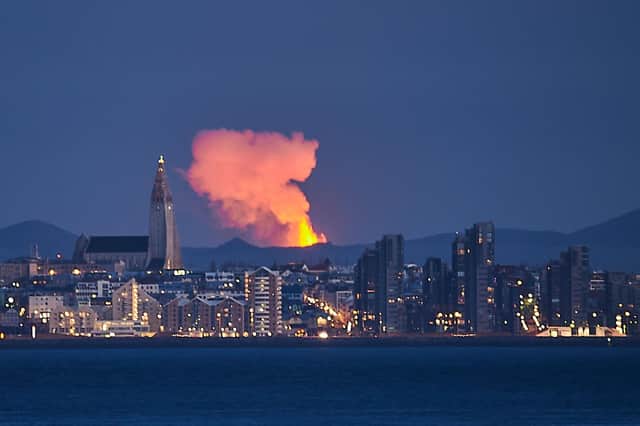 Icelandic capital Reykjavik is seen with the glow from the lava coming out of a volcanic fissure on the Reykjanes Peninsula behind in May this year (Picture: Halldor Kolbeins/AFP via Getty Images)
