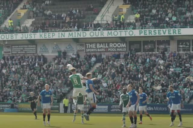 Doidge wins the ball in the air to set up Josh Campbell (not in picture) for the equaliser against Rangers with the 'persevere' motto in the background