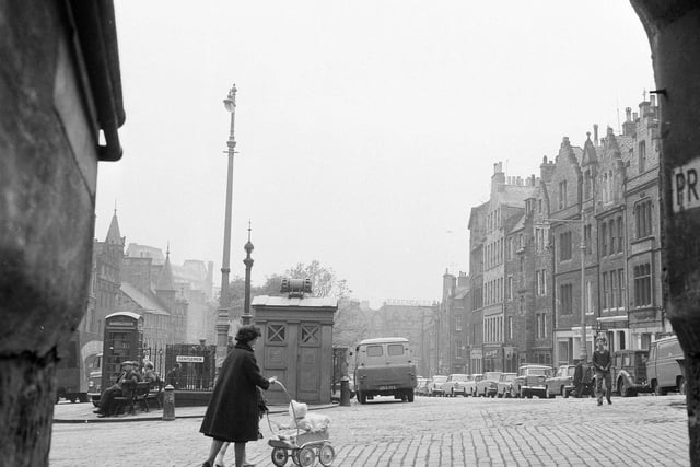 Here, a woman is seen pushing a pram past the police box and former gents' toilets in the Grassmarket in 1965.