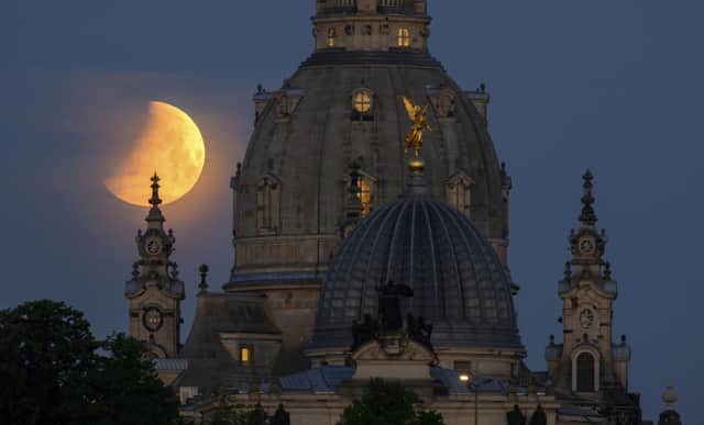 The moon during a partial lunar eclipse behind the Frauenkirche and the dome of the Kunstakedmie in Dresden, Germany (Robert Michael/dpa via AP)