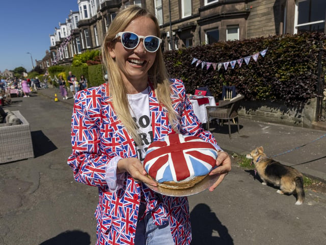 A woman poses with a Union Jack flag cake as residents of Netherby Drive in Trinity celebrate the Platinum Jubilee. (Photo by Robert Perry/Getty Images)